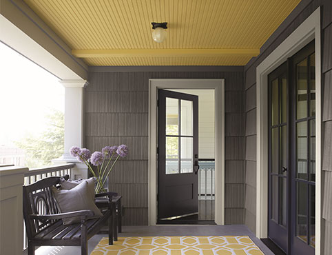A covered porch area with a yellow ceiling painted in Marblehead Gold HC-11.