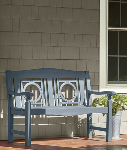 Maison recouverte d'un parement en vinyle avec des moulures peintes en blanc et un banc bleu-gris