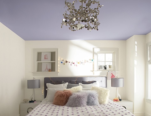 An airy teen bedroom with ceiling in light purple paint colour.