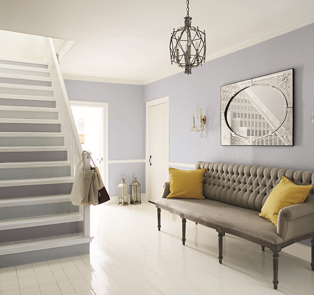 Une entrée bleu-gris pâle et blanc avec des meubles aux accents classiques.