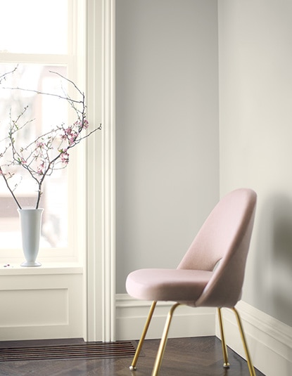 A pink chair frames a wall painted in Balboa Mist OC-27.