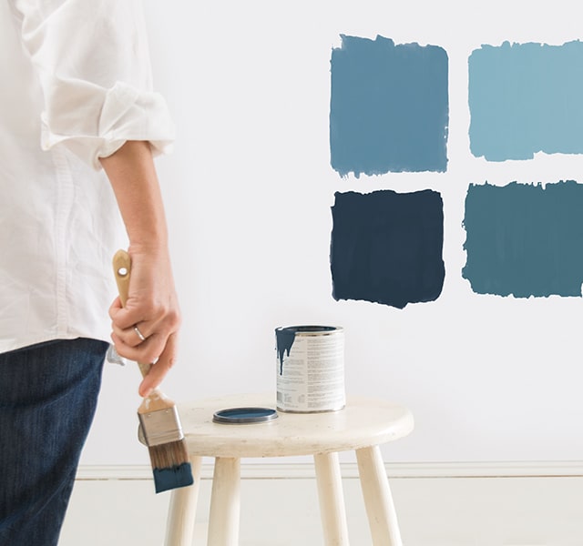 A homeowner sampling different interior blue paint colours.