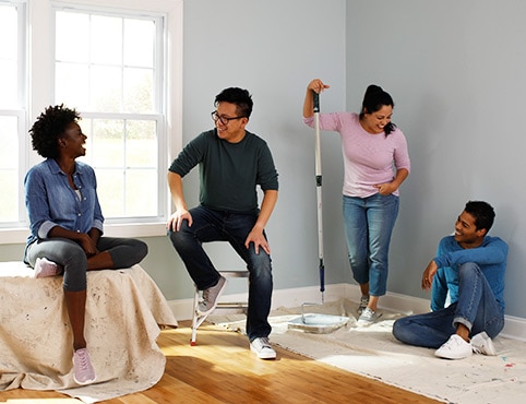 Four young adult friends gather in a room that they are painting.