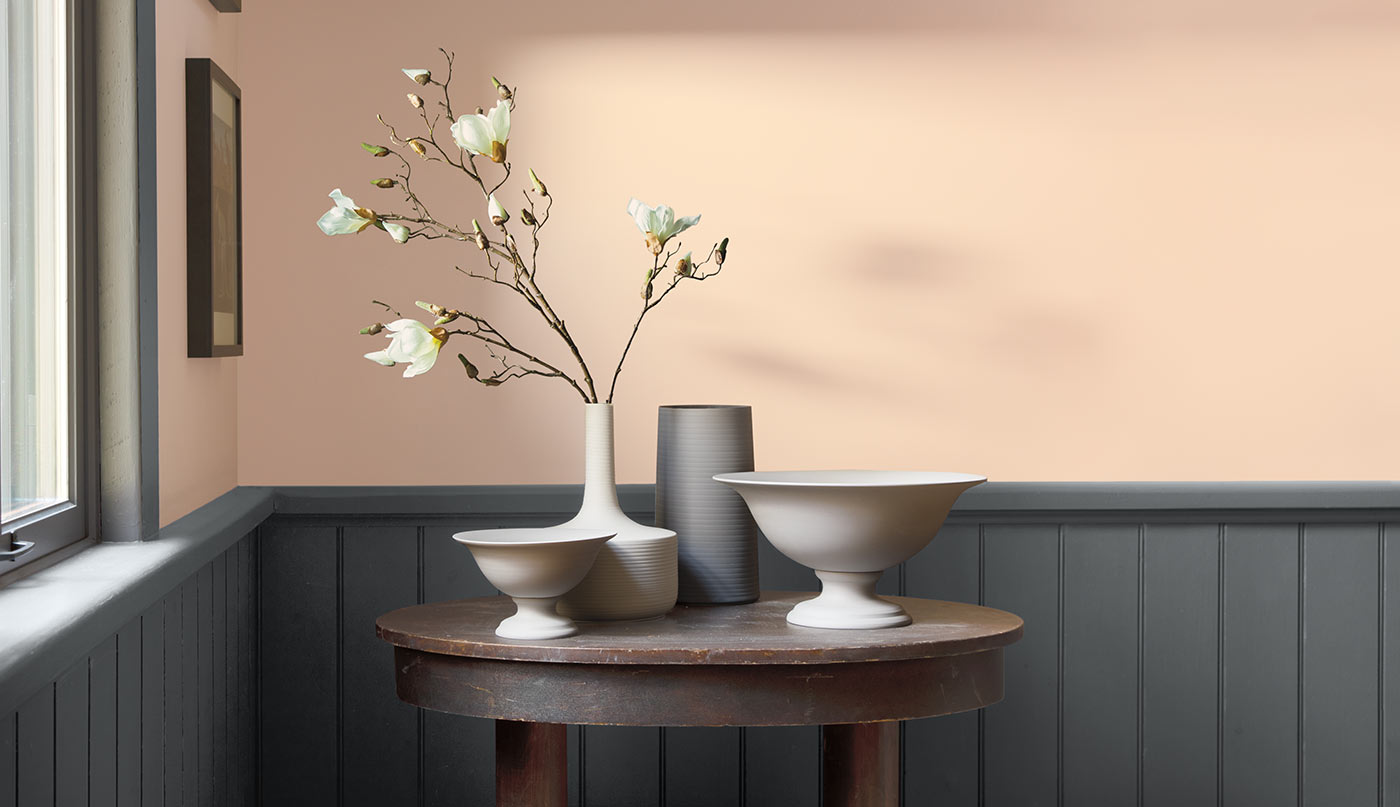 A light peach-painted room contrasted by dark gray wainscotting.