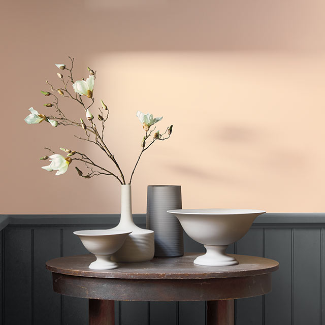 A light peach-painted room contrasted by dark gray wainscotting.