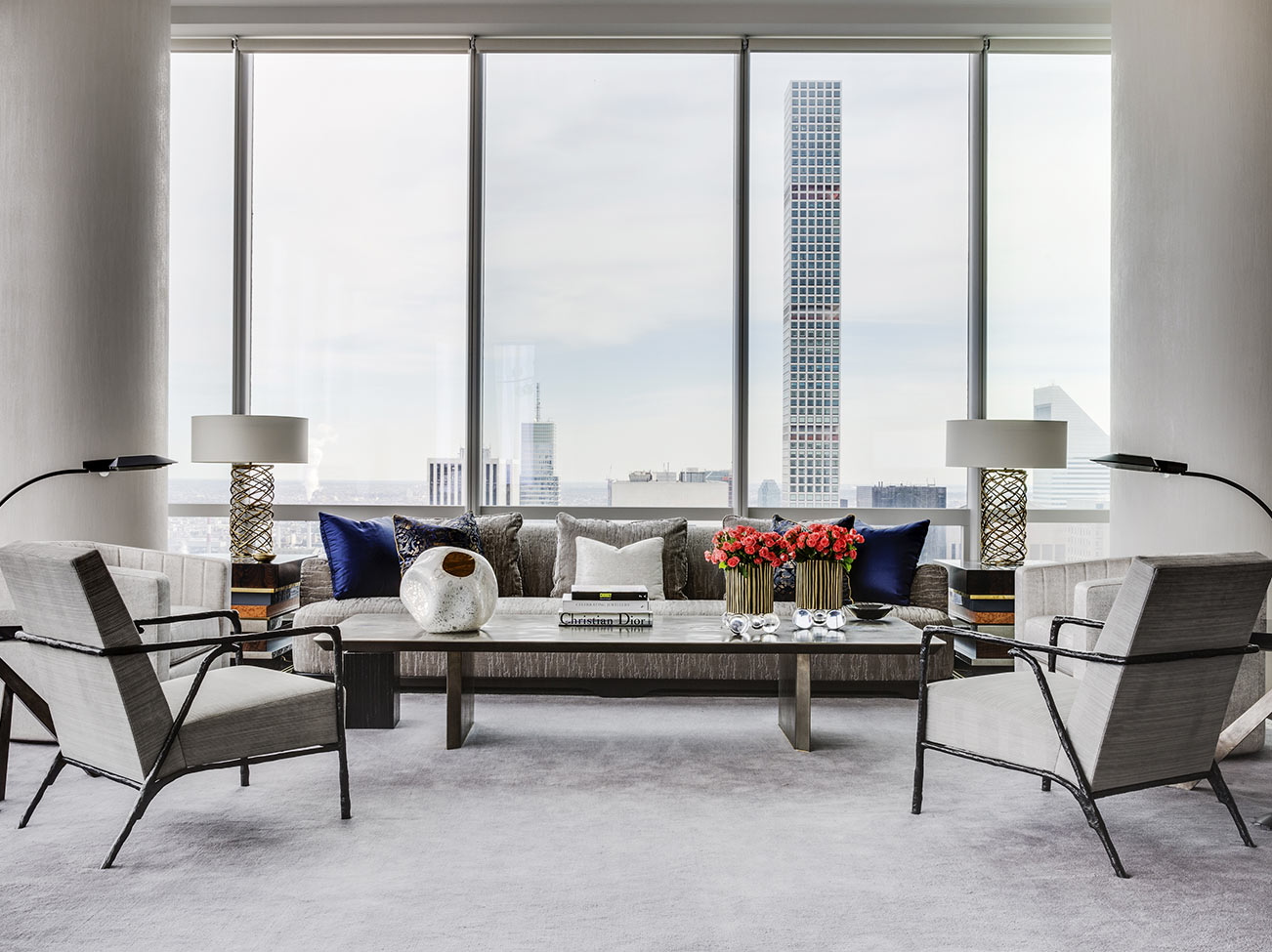 A sleek, white-painted living space with modern furnishings and massive floor to ceiling windows overlooks a cityscape.