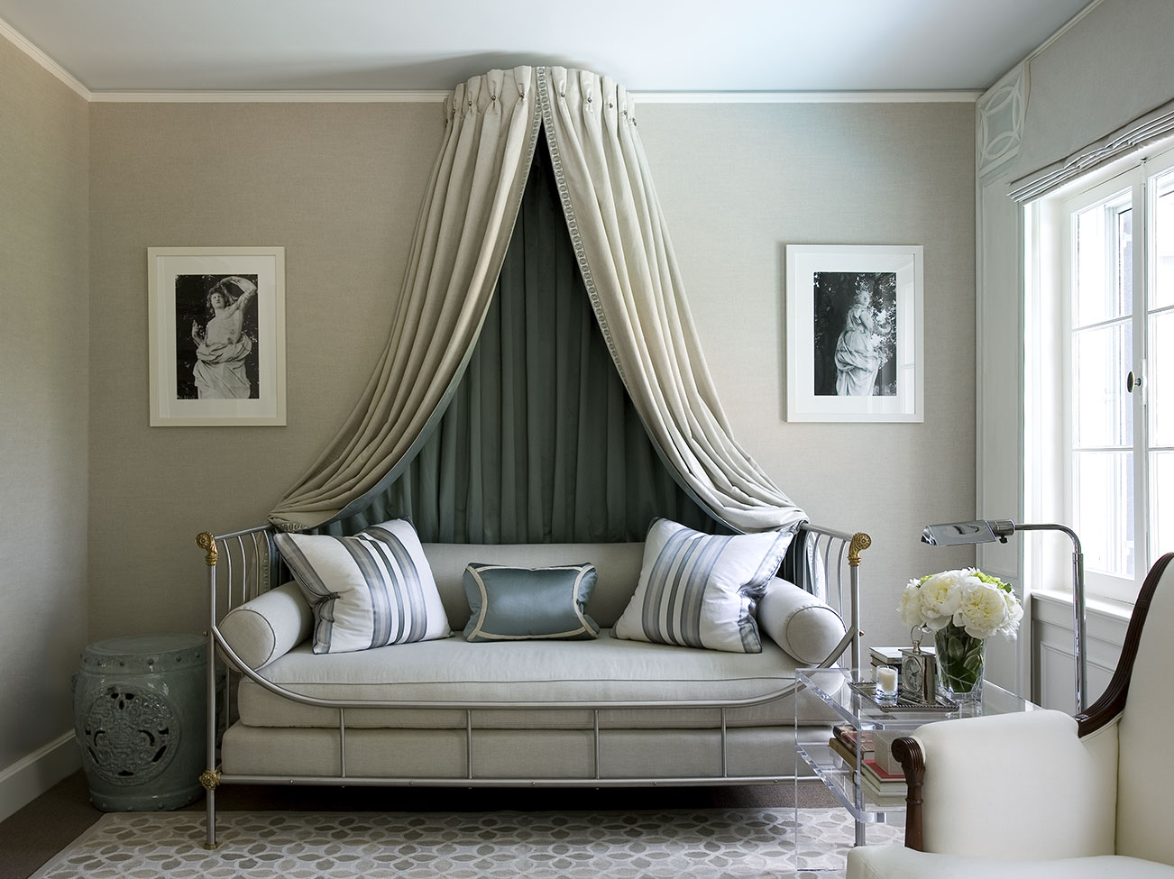 Sitting room in neutral tones with sky blue-painted ceiling, cushioned day bed with draped canopy, and striped pillows.