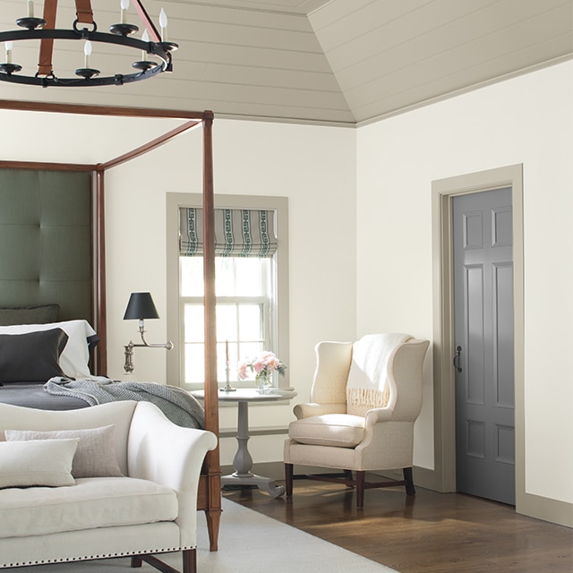 Une chambre à coucher gris et blanc présentant un plafond surélevé aux riches accents et un plancher de bois franc.