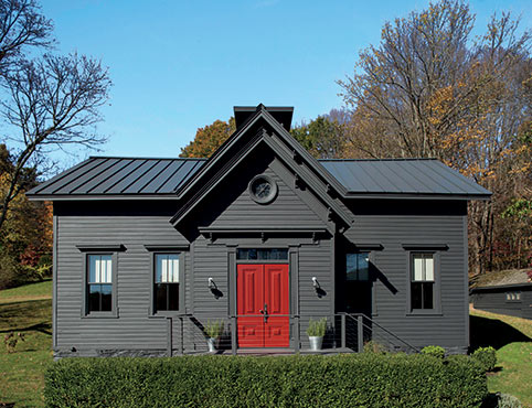 A home with a dark red-painted front door adds a pop of color to a gray-black-painted exterior.