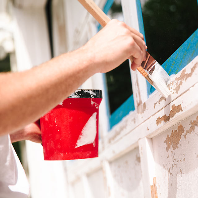 A person applies primer to a garage door before painting it.