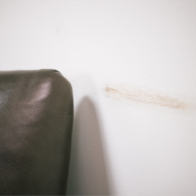 Une marque de frottement sur un mur blanc, derrière un canapé en cuir.