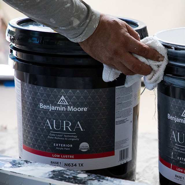 Two pails of AURA® Exterior Paint being wiped down by a Painting Contractor.