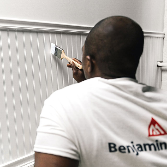 A painting professional paints a wall with ben Interior paint.