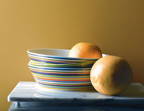 Dinner plates in variety of bright colors against yellow wall
