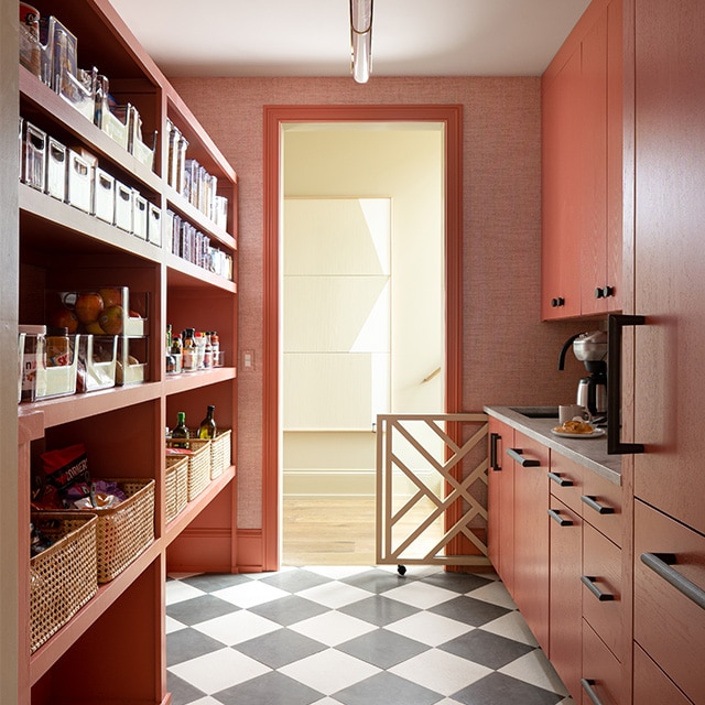 Une étroite arrière-cuisine avec des étagères et des armoires de couleur rose, un plafond blanc et un plancher à damier.