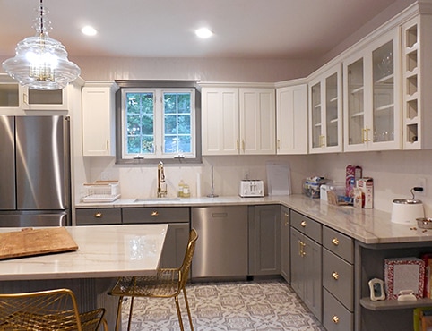 After photo of a large repainted two-toned kitchen featuring white upper cabinets and gray lower cabinets with a matching gray island.
