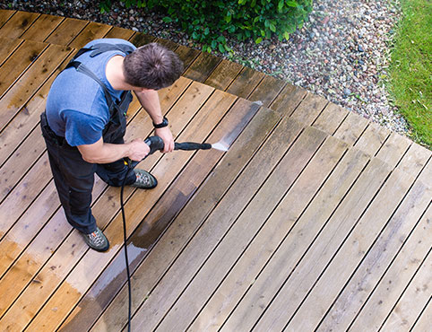Contractor power washing a deck in preparation for restaining.