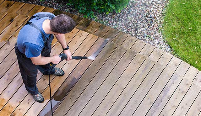 A painting contractor power washing a deck.