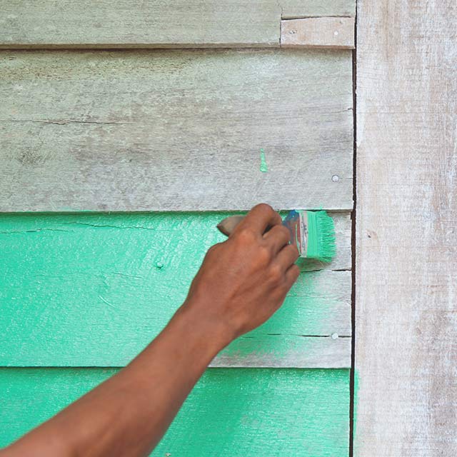 A wood surface being painted in a teal color