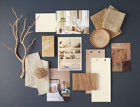 White and neutral paint chips, home interior photos and other natural accents lay atop a navy blue-painted surface.