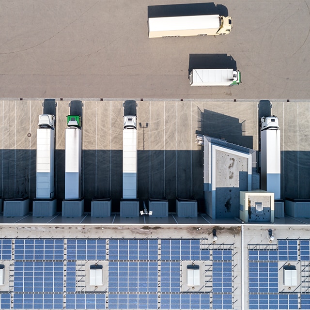 Una vista aérea de camiones de entrega estacionados en las plataformas de carga de un almacén. Una vista aérea de camiones de entrega estacionados en las plataformas de carga de un almacén.