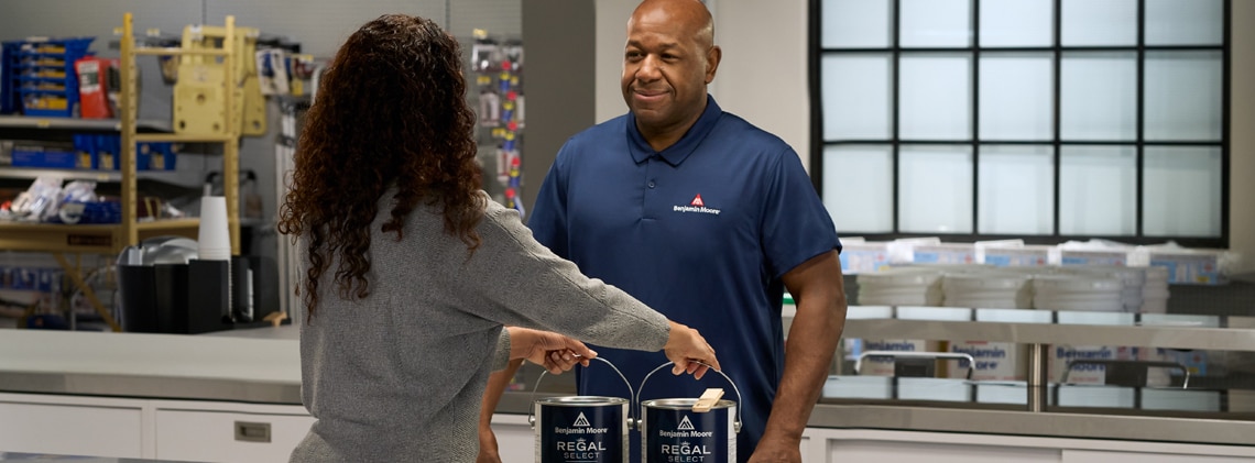 A Benjamin Moore Store professional sells gallons of Regal® Select interior paint to a customer.
