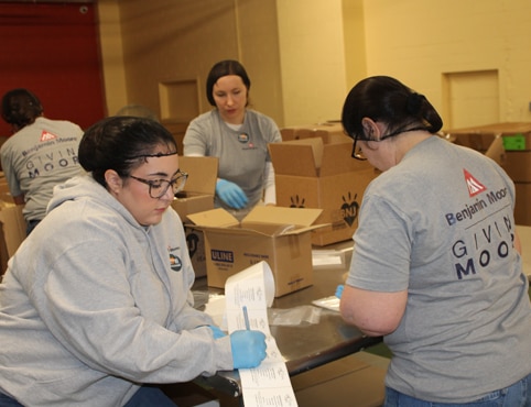 A group of Benjamin Moore employee volunteers preparing and labeling boxes.