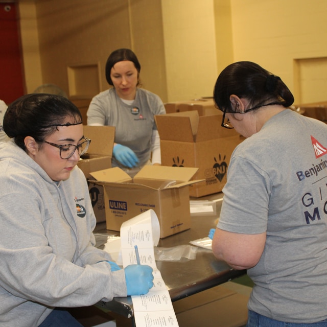 A group of Benjamin Moore employee volunteers preparing and labeling boxes.