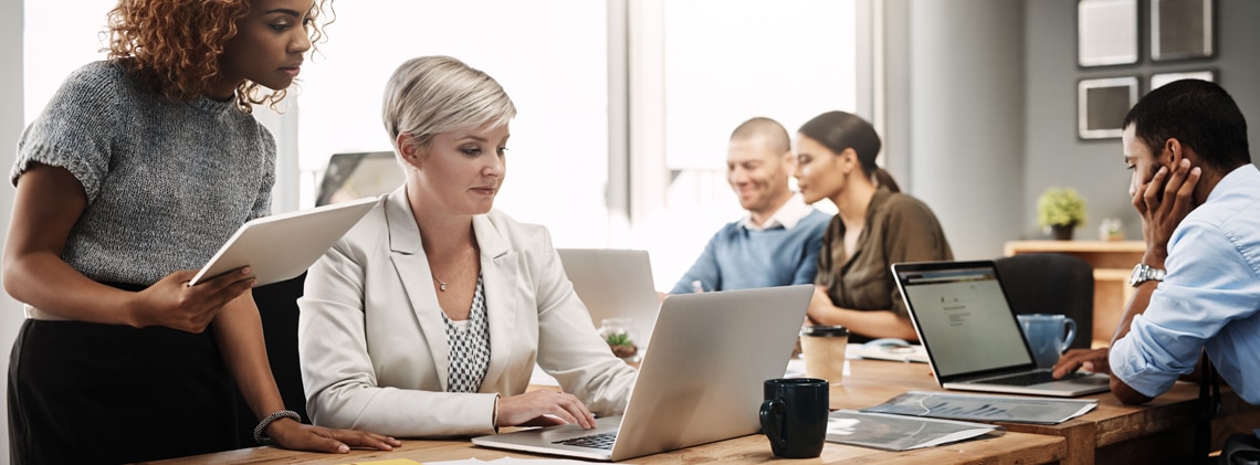 A group of Benjamin Moore employees gathered in a meeting room with open laptops.