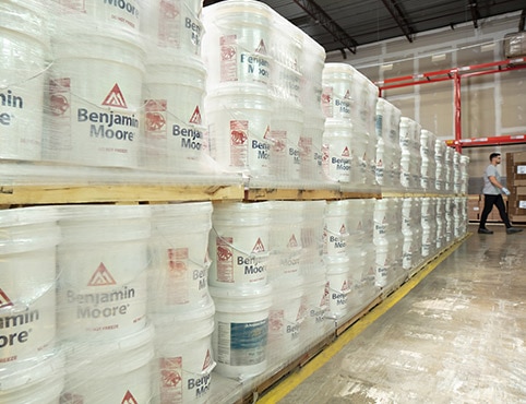 Five gallon containers of Benjamin Moore premium paint in a warehouse.