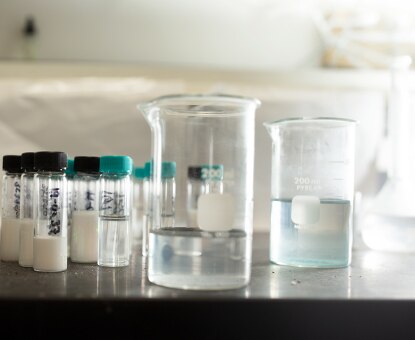 Vials filled with powder and liquid, two large beakers with liquid shown in the Benjamin Moore lab.