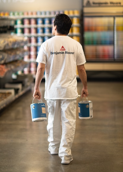 A Benjamin Moore painting contractor walks through a Benjamin Moore store carrying two cans of Regal® Select Interior paint. A Benjamin Moore painting contractor walks through a Benjamin Moore store carrying two cans of Regal® Select Interior paint.