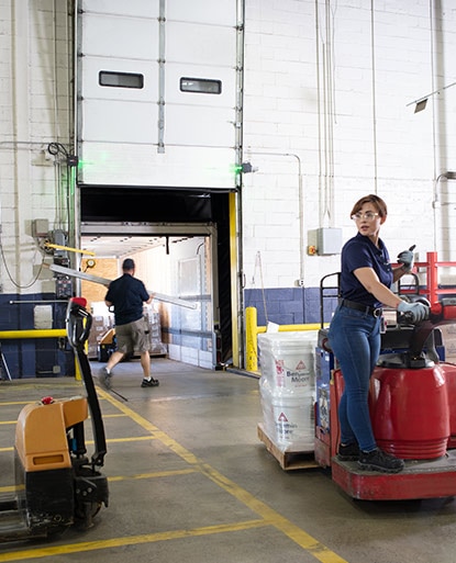 Benjamin Moore employees working in a warehouse, using machinery and carrying items.