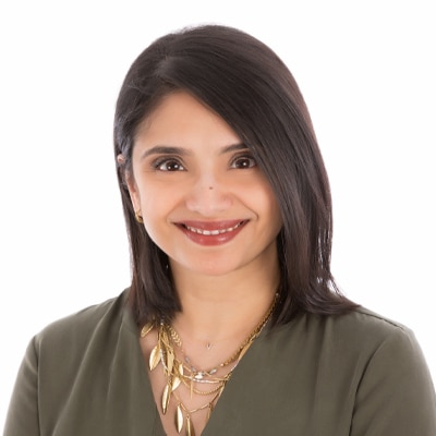 A head shot of a brunette woman with a green blouse.