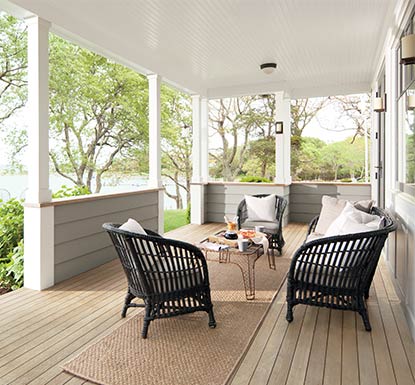 A backyard porch overlooking a lake with a boat features a deck and railings stained in ARBORCOAT Translucent in Silver Gray.