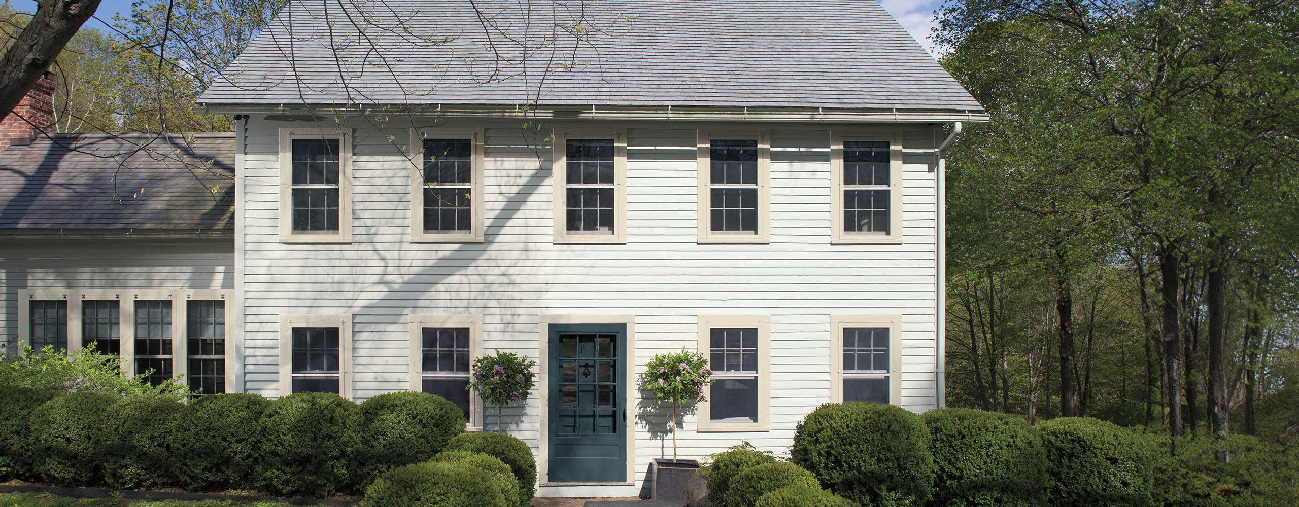 Residential exterior featuring Colonial saltbox with shrub-lined front walk.