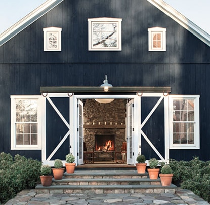 Dark blue barn exterior with large stone walkway with stairs