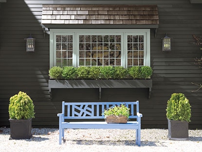 Banc bleu à l'extérieur de la maison avec plantes sur le bord de la fenêtre Banc bleu à l'extérieur de la maison avec plantes sur le bord de la fenêtre