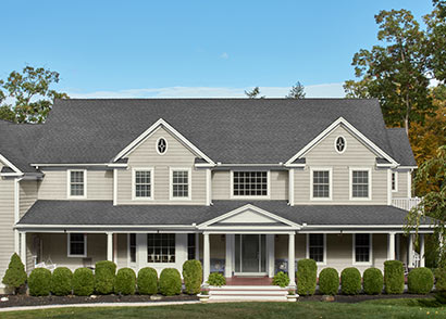 A light gray coloured house with vinyl siding and a dark gray front door