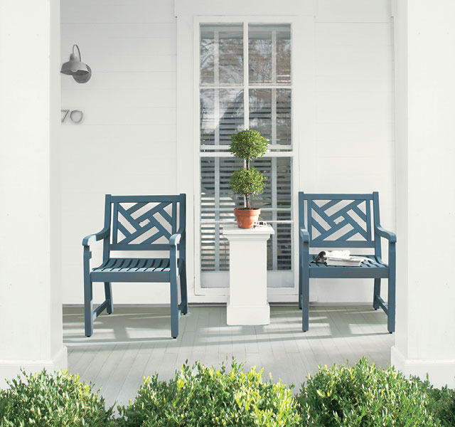 White front porch with blue chairs all stained in ARBORCOAT® Exterior Stain, Solid with porch floor in Cliffside Gray HC-180, Chair in Hamilton Blue and Siding in White.