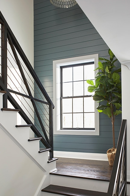 A stairway with white walls, gray trim and risers, and a shiplap accent wall in blue gray.