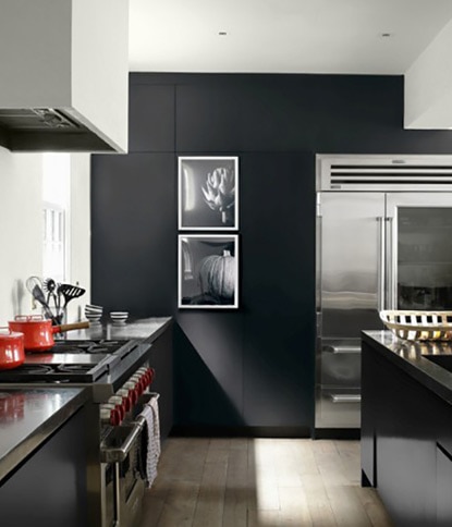 A slick kitchen with black accent wall, white ceiling and walls, black counters, and silver appliances.