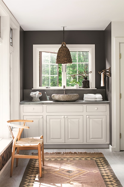 Black bathroom walls with white vanity and moroccan rug.