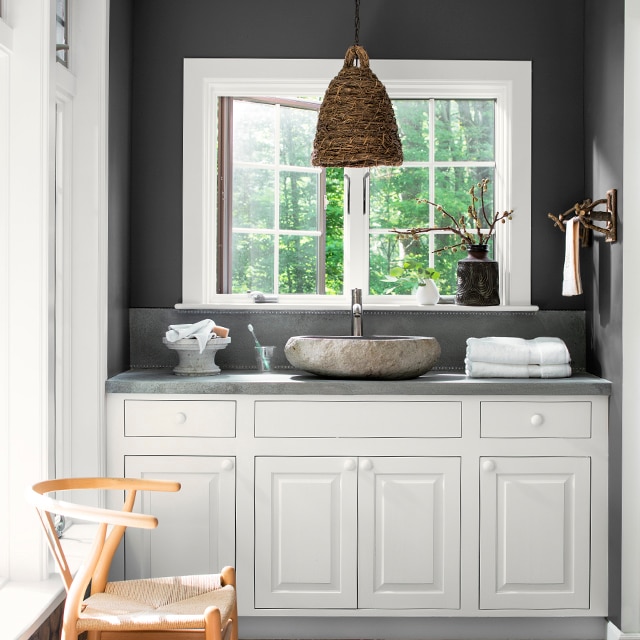 Black bathroom walls with white vanity and moroccan rug.