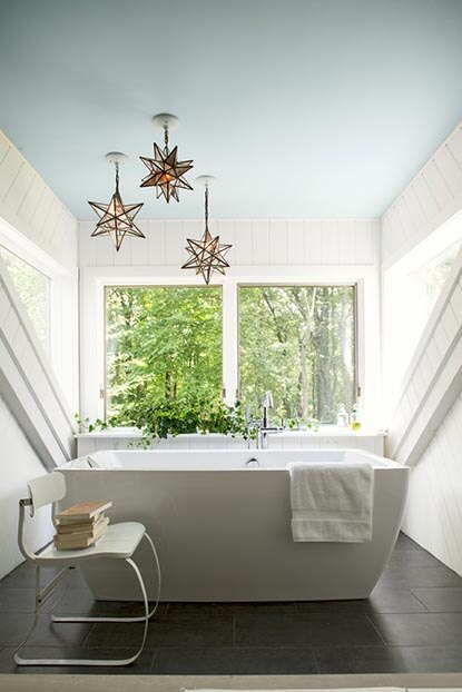 Une salle de bains au plafond bleu pâle avec un bain moderne de couleur blanche.