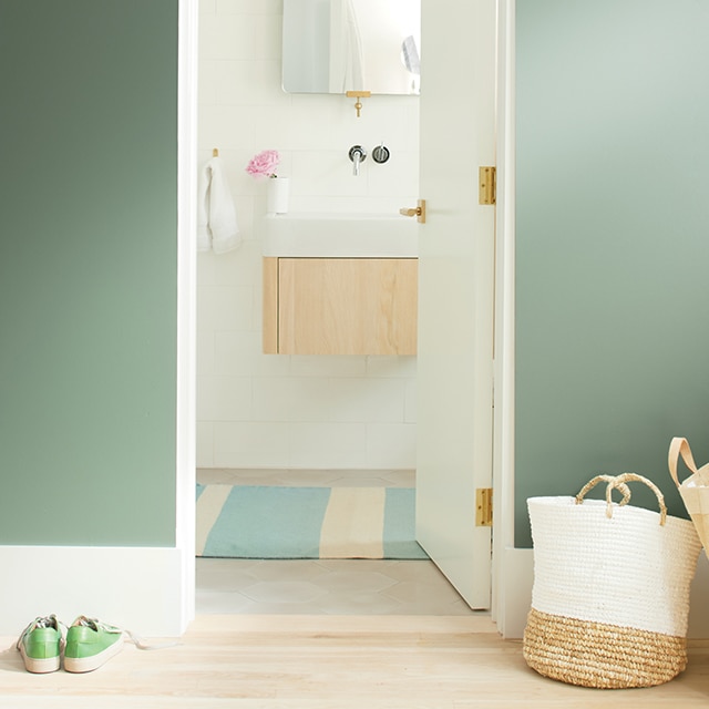 Mur vert avec porte blanche ouverte sur une salle de bains blanche.