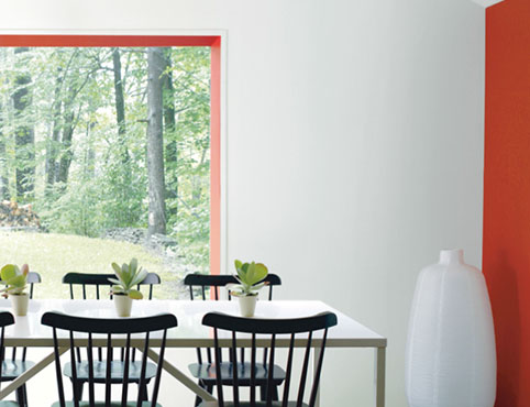 White dining room with orange accent wall and black dining chairs. White dining room with orange accent wall and black dining chairs.