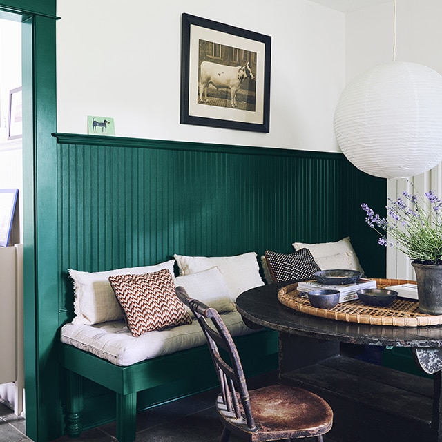 A charming dining area with green painted trim, beadboard wainscotting, and bench, white upper walls, and a rustic wooden table and chair. A charming dining area with green painted trim, beadboard wainscotting, and bench, white upper walls, and a rustic wooden table and chair.