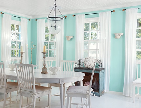 Jolie salle à manger turquoise clair aux moulures blanches avec plafond blanc en planches à feuillure et mobilier blanc. Jolie salle à manger turquoise clair aux moulures blanches avec plafond blanc en planches à feuillure et mobilier blanc.
