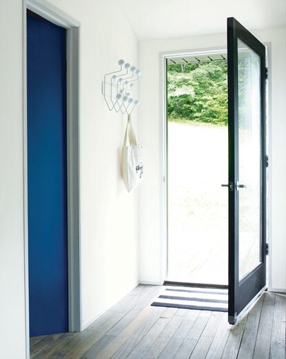 A crisp, white entryway features natural light flooding through a contemporary door.